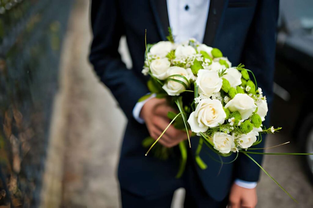 Groomsman holds two bouquets for bridesmaids