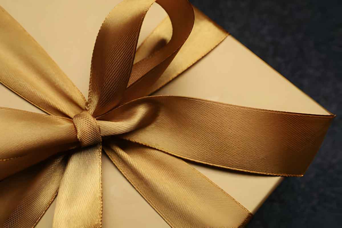 Close-up of a golden gift box adorned with a satin bow.