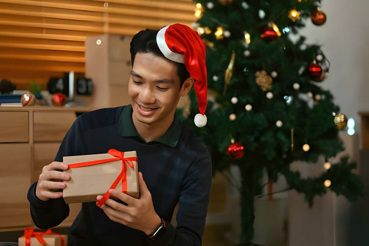 Young man eagerly looks at a gift box, anticipating the surprise inside.